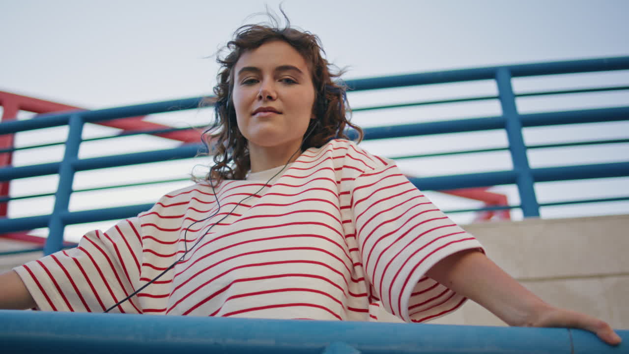 adolescente escuchando auriculares sonido mirando cámara en la calle de cerca. chica disfrutando
