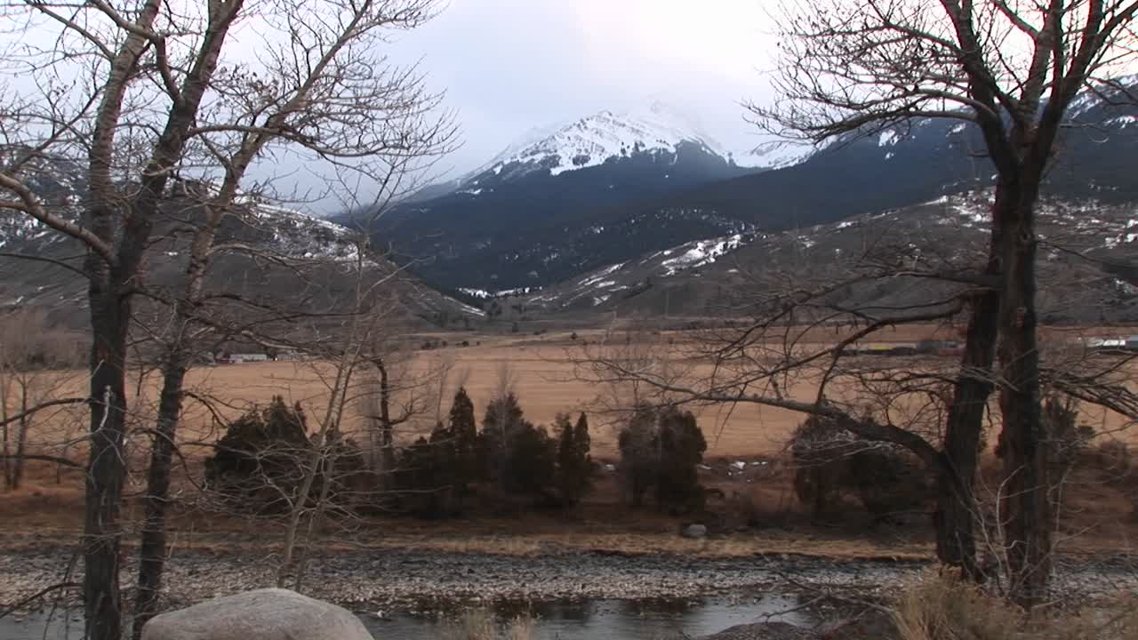 En tørr vinterprærie er omkranset av åser og fjell i bakgrunnen.