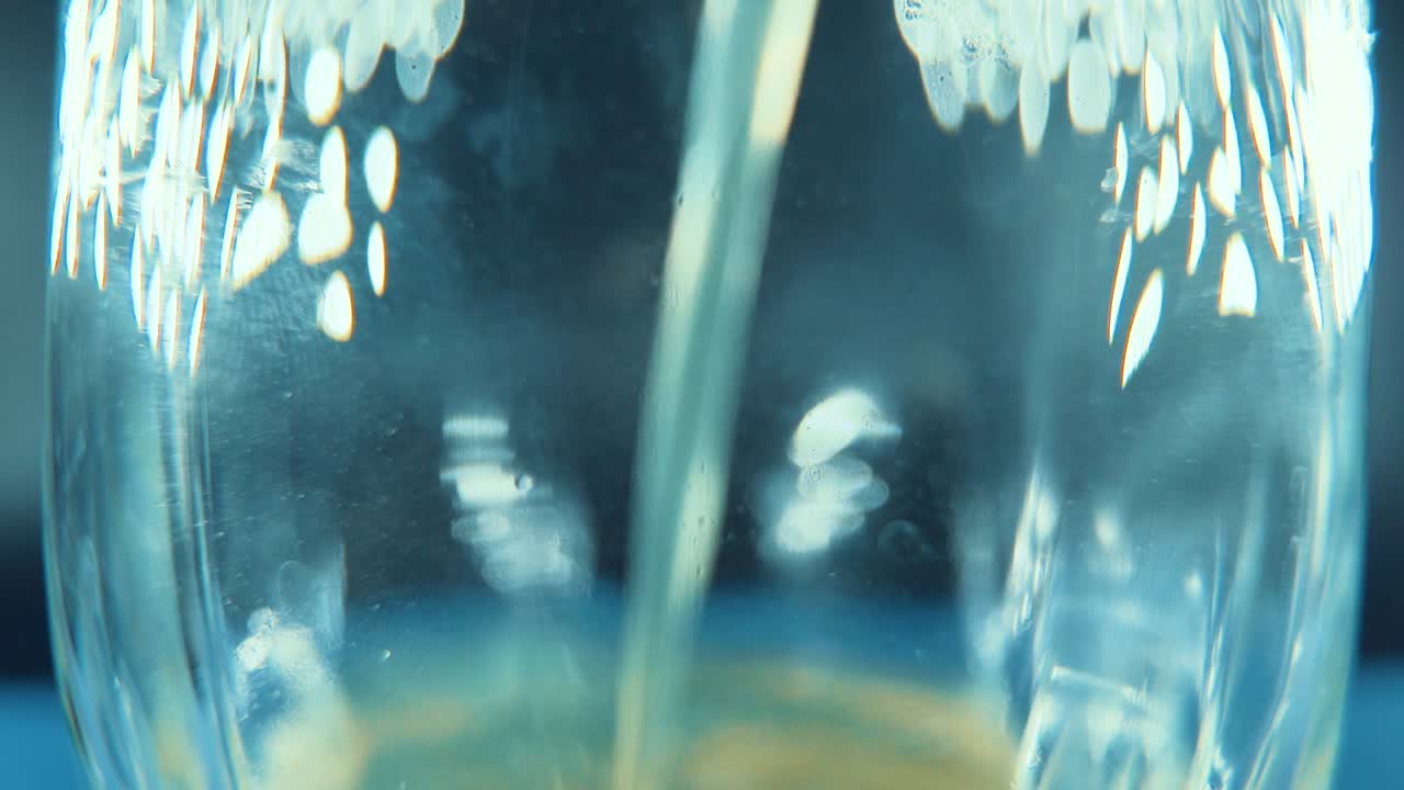 A macro shot of a filling glass with orange juice, studio lighting, 120 fps slow motion, Full HD