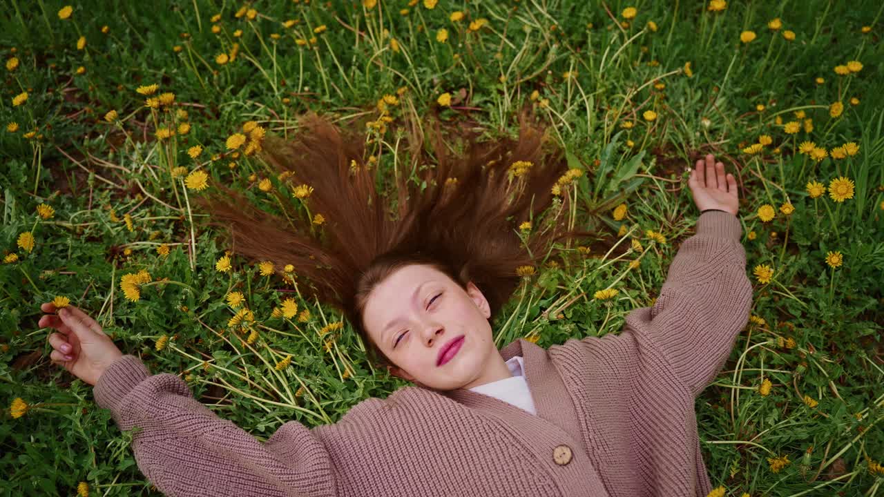 Teenage girl relaxing in a field of dandelions