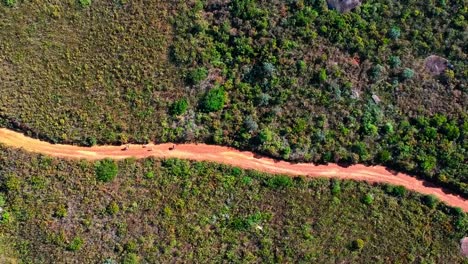 Eine-Zurückgezogene-Drohnenansicht-Von-Menschen,-Die-Auf-Einer-Unbefestigten-Straße-Am-Hang-Eines-Steilen-Hügels-Wandern