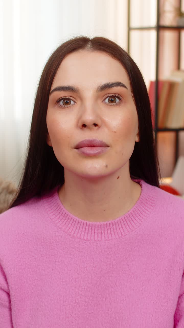 Young woman sitting on sofa raising eyebrows opening mouth surprised amazed shocked by unexpected