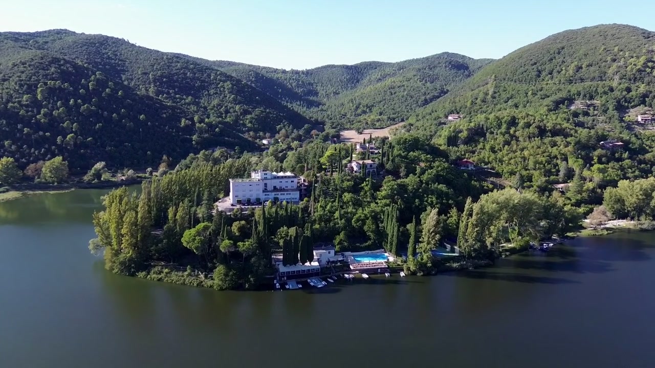 Riprese aeree con drone di Piediluco, Umbria, Italia, che mostrano la città lacustre circondata da montagne verdi, acque blu calme e una campagna panoramica sotto un cielo limpido