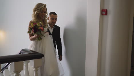 woman in wedding dress and groom in classic suit in building