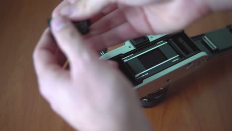 Loading-color-film-into-old-analog-SLR-camera,-4K-close-up-fast-forward-footage