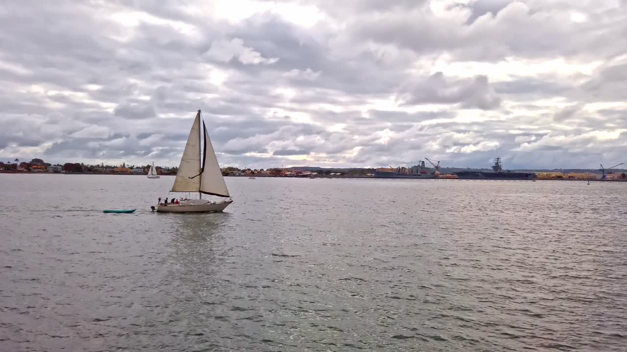 Lonely sail floating on San Diego bay near Coronado bridge at sunset. Cloudy sky. Panoramic shot