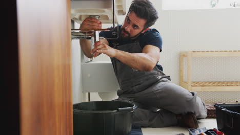 Plomero-Masculino-Trabajando-Para-Arreglar-El-Lavabo-Con-Fugas-En-El-Baño-De-Su-Casa