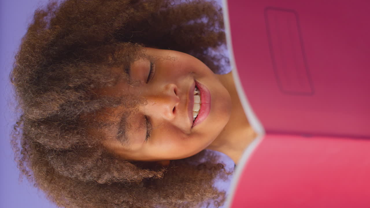 вертикальное видео молодого мальчика, изучающего школьный учебник на фиолетовом фоне