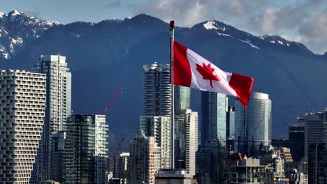 the canadian flag stands tall against a striking city skyline and mountain backdrop, with downtown views from south granville in vancouver, canada - zoom in shot