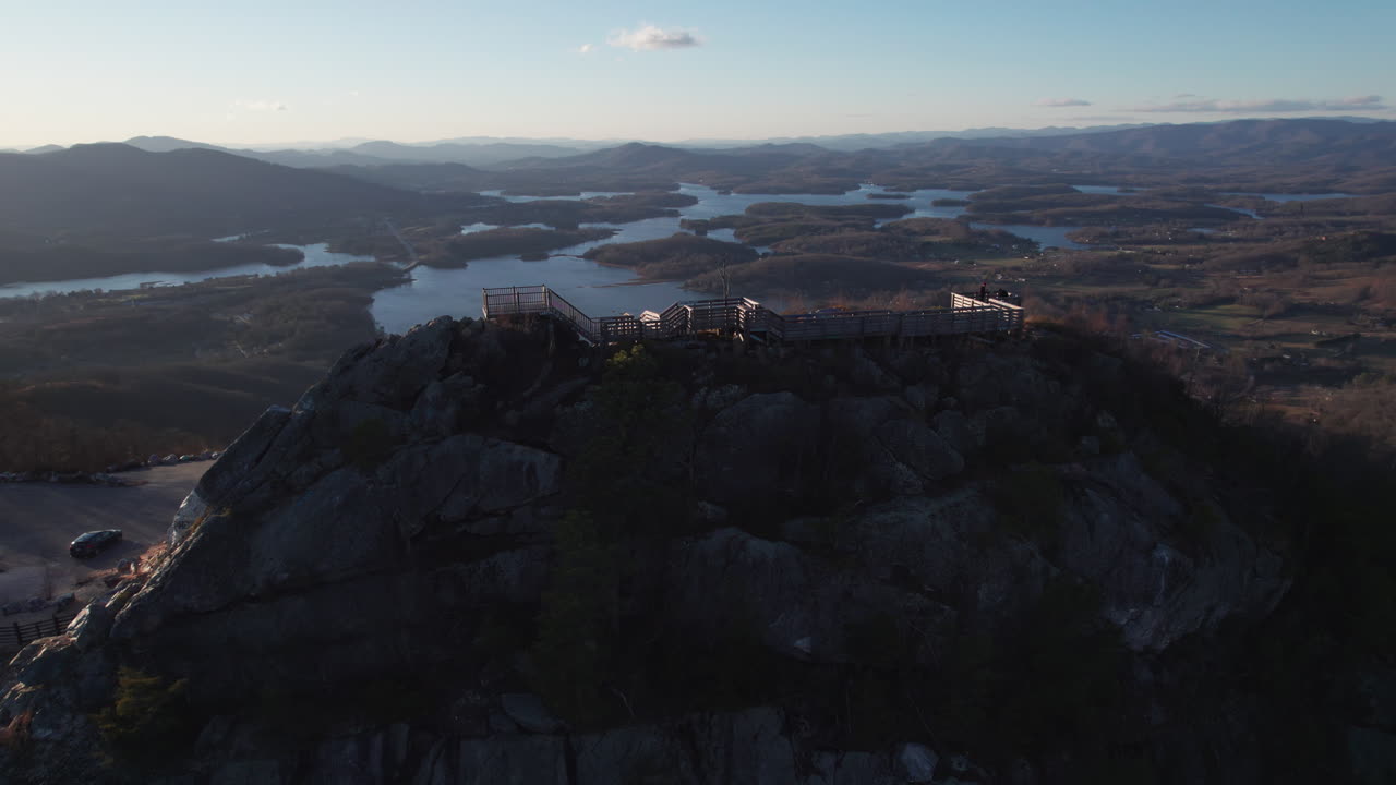Epic sunset aerial of Bell Knob, a popular tourist hiking location for panoramic views, revealing scenic views of the Lake Chatuge reservoir landscape in the north Georgia mountains near Hiawassee.