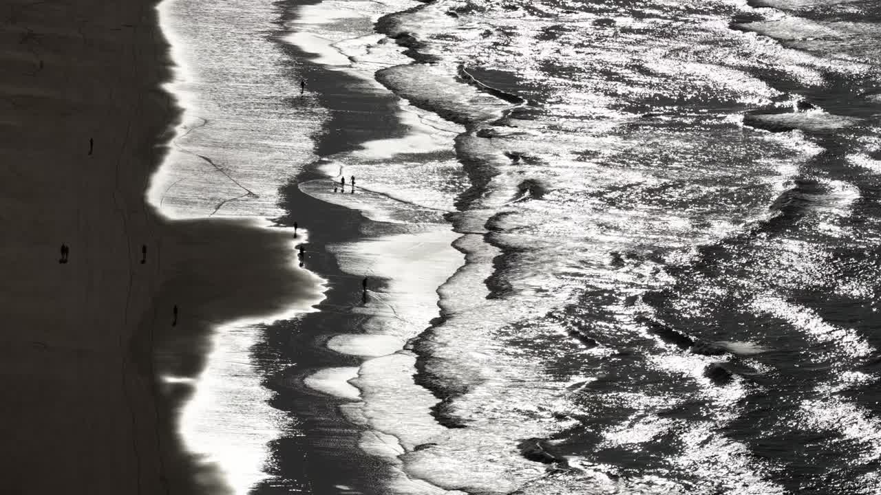 People silhouettes walking on the beach