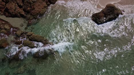 small-waves-break-on-tropical-sand-with-rocks