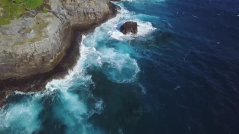 gorgeous waves crashing on spitting cave in honolulu hawaii with fancy homes and greenery - aerial dolly tilt reveal