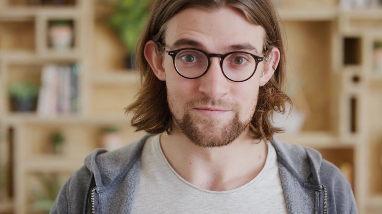 Young Man Putting On Glasses and Looking at Camera