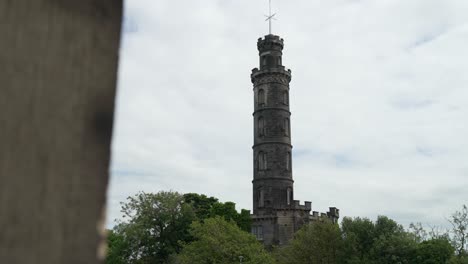 la gaviota volando en el cielo frente al monumento a nelson en edimburgo, escocia.