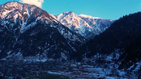 sunlit snowy peaks over a valley with a village