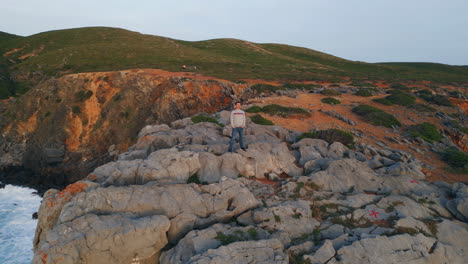 calm person relaxing rocky highland at seashore. man standing volcanic cliffs