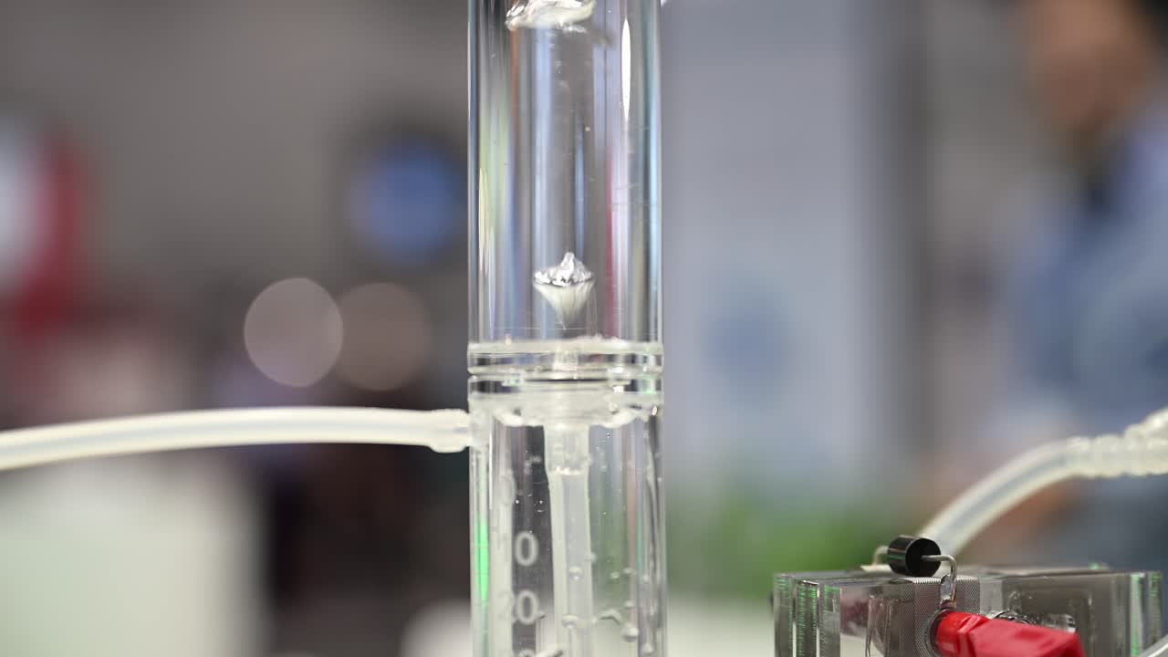 burbujas de hidrógeno que se forman en un cilindro de plástico lleno de agua, demostrador de células de combustible que divide el agua en oxígeno e hidrógeno