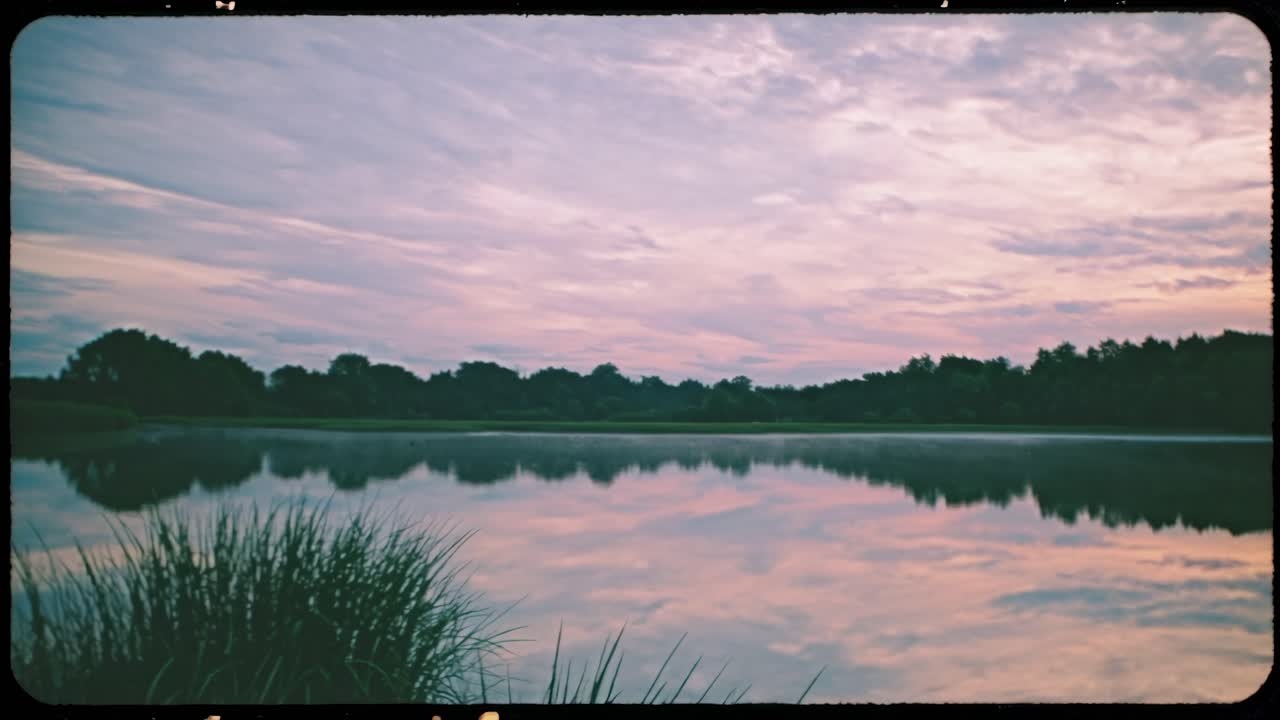 Serene lake at sunset with calm water reflecting the sky. Peaceful lake scene with lush greenery