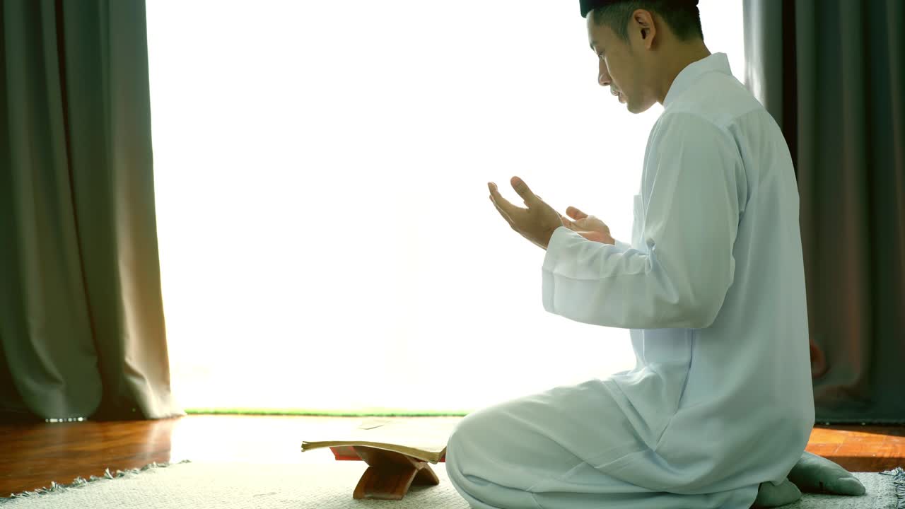 아시아의 무슬림 남자가 집에서 기도하고 드리고 있습니다.