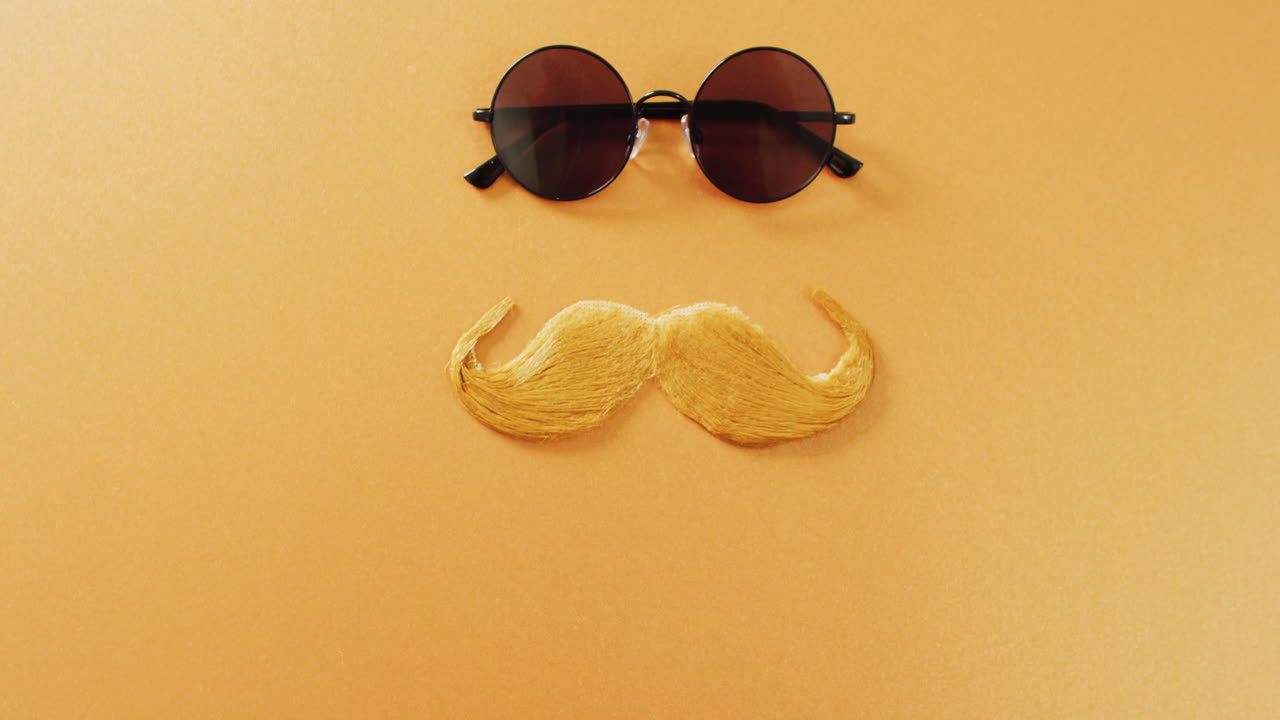 Video of blonde false moustache and round sunglasses on yellow background