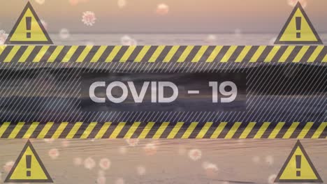 video compuesto digital de señales de advertencia amarillas con texto de covid-19 y células que se mueven contra la playa en