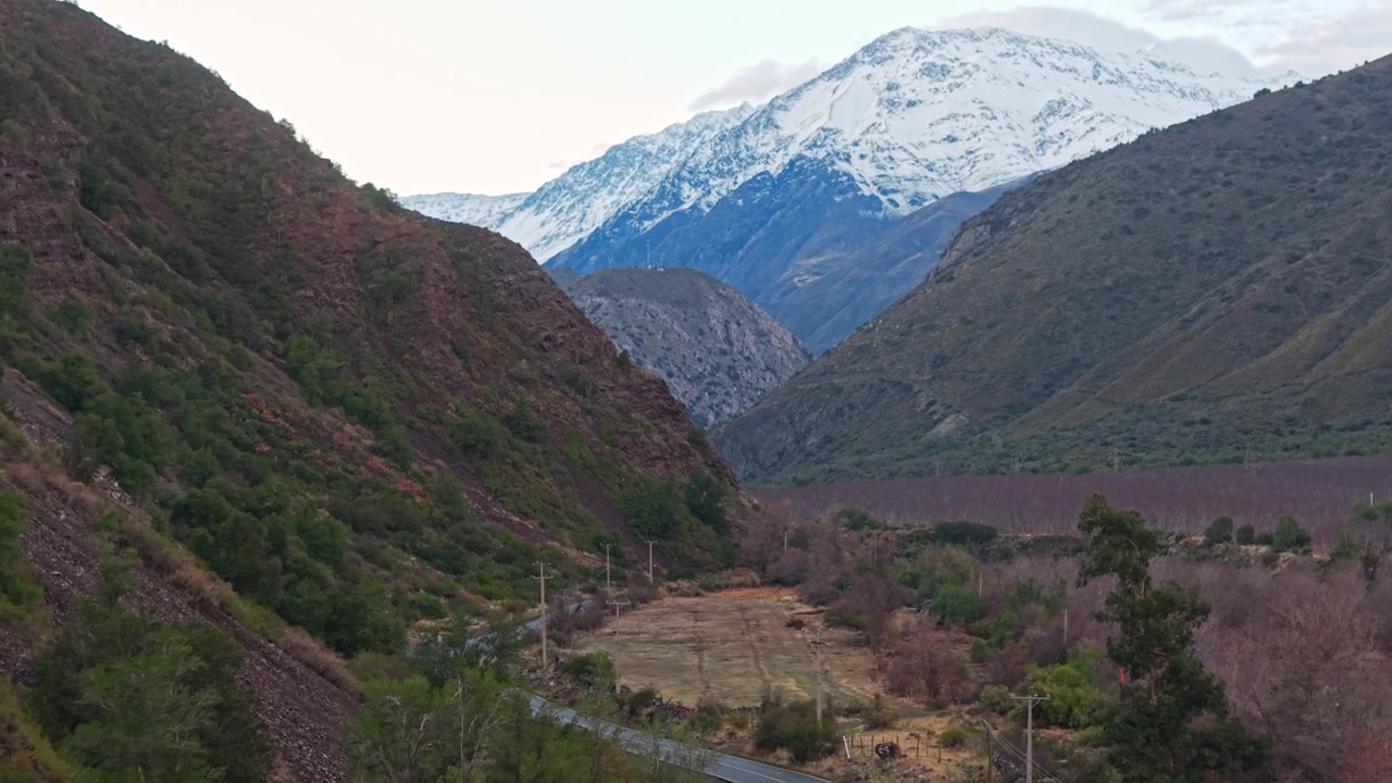 Carrellata con teleobiettivo lungo l'unica strada attraverso il Cajon del Maipo verso le montagne innevate delle Ande, Cile.