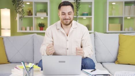 Hombre-Sentado-En-Casa-Regocijándose-Por-Lo-Que-Ve-En-La-Pantalla-Del-Portátil.