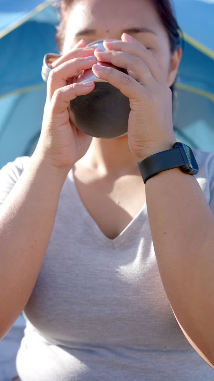 Vertikal video: Drikker af feltflaske, kvinde med smartwatch vandrer på bjergsti