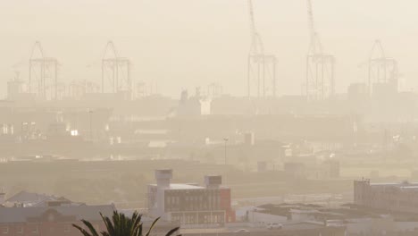 general view of cityscape with multiple buildings and shipyard covered in fog