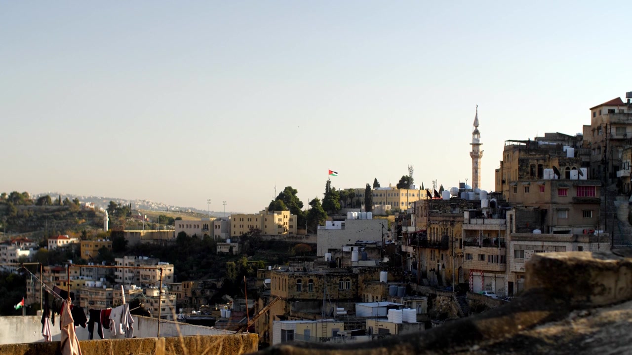 Vista panoramica di edifici storici e case sulle colline di Amman durante una leggera foschia al tramonto. Espansione urbana tradizionale mediorientale e quartiere residenziale in Giordania.