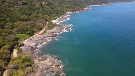 Costa-Rica,-Rocky-Stone-Coast-with-waves-splashing-aginst-the-stones,-Dji-Drone-Shot