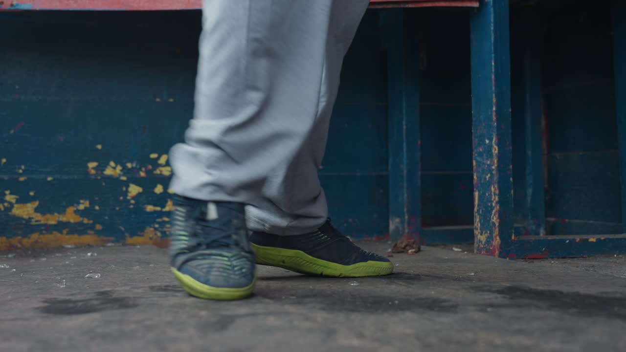 도시 환경에서 리듬감 있는 발놀림을 선보이는 모습이에요. 콘크리트 바닥 위에서 발이 춤 동작을 하는 클로즈업 장면, 도시 배경에서 춤을 추는 동안 신발이 회전하고 움직이는 디테일 샷입니다.