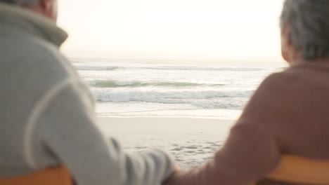 sunset, beach and senior couple on chair by ocean