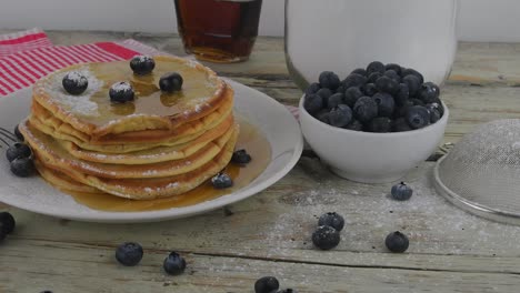 pila de panqueques de leche de mantequilla estadounidense con bayas y jarabe de arce. sabrosos alimentos dulces para el desayuno. panqueques en fondo rústico blanco.