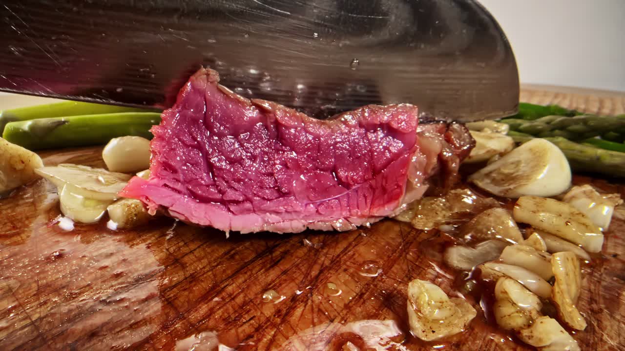 Taglio di una succosa bistecca al sangue su un tagliere di legno