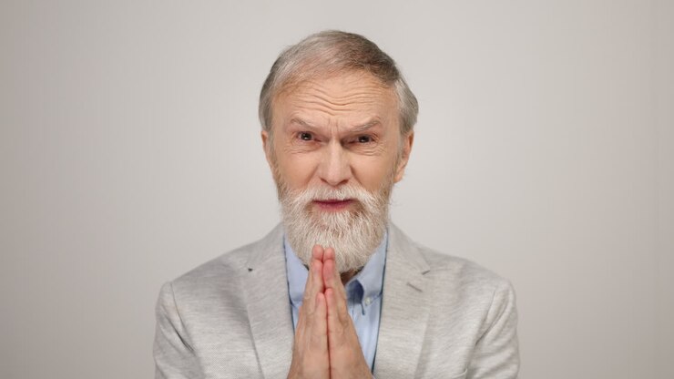 Uomo preoccupato che chiede aiuto in studio. Anziano che giunge le mani in preghiera in interni