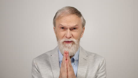 worried man asking for help in studio. old guy putting hands for pray indoors.