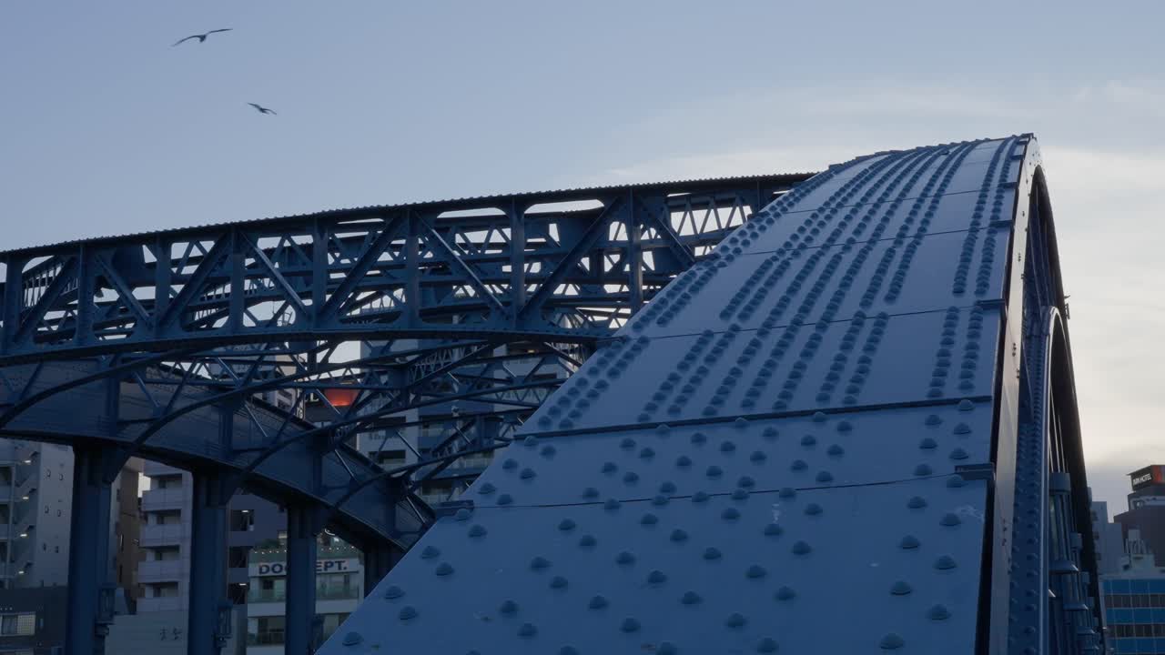 Uno scatto che cattura il caratteristico arco blu del Ponte Komagata sul fiume Sumida contro un cielo crepuscolare.