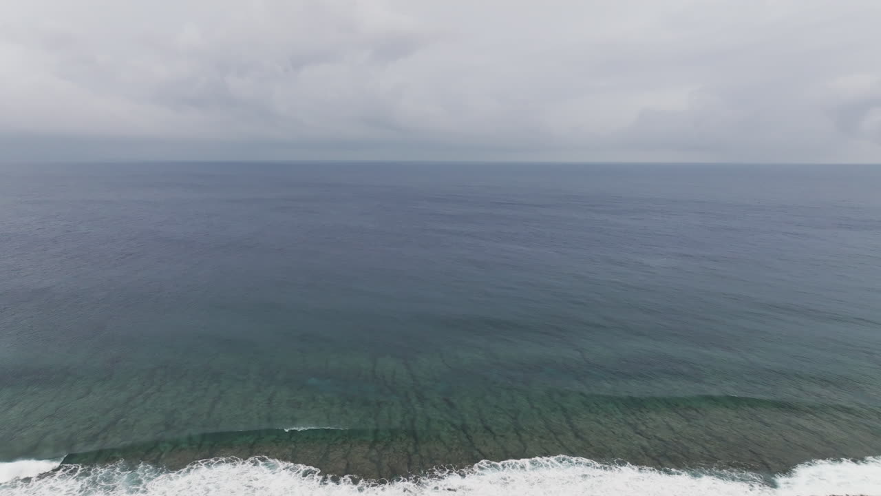Droen flyby shot over empty South Pacific Ocean under heavy dense clouds in Cook Islands.
