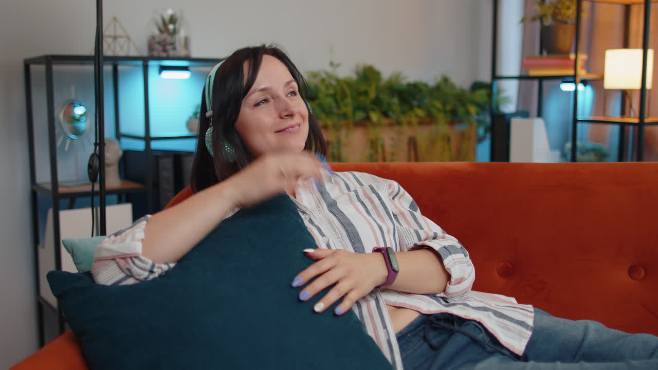 chica feliz y relajada con auriculares inalámbricos bailando escuchando su música rock n roll favorita en el sofá de casa