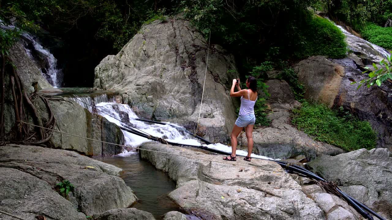 A woman photographing a waterfall