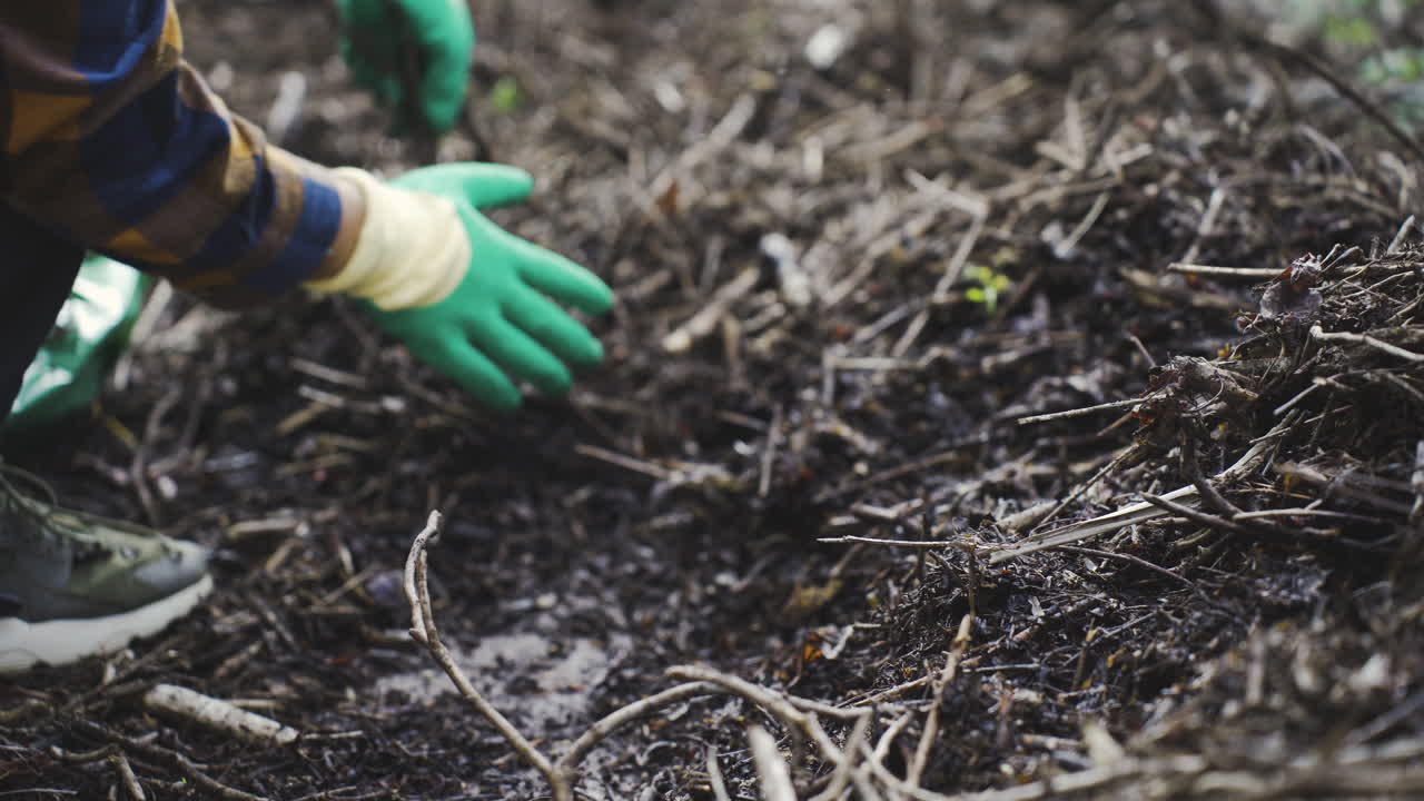 mani chiuse con i guanti che raccolgono i rifiuti organici del giardinaggio