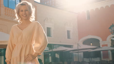 stylish woman in a light beige dress in a sunny city