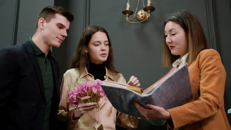 asian woman showing a sample book to a couple