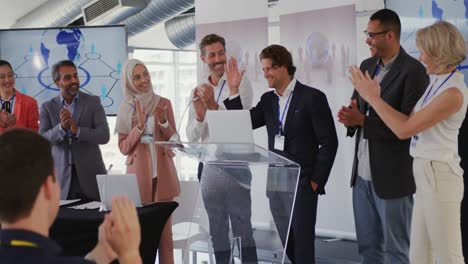 Male-speaker-and-applauding-audience-and-colleagues-at-a-business-presentation