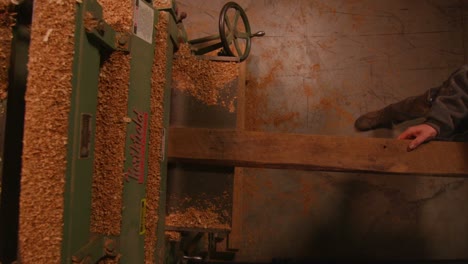 Overhead-view-of-woodworkers-passing-a-plank-through-a-machine-in-a-woodshop