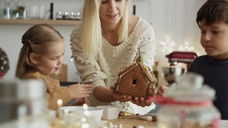 video de una familia decorando juntos una colorida casa de pan de jengibre