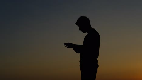 silhouette of teenager smoking while using phone