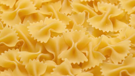 Montón-De-Pasta-Farfalle-Italiana-Cruda-En-Movimiento,-Vista-De-Primer-Plano-Giratoria,-Concepto-De-Presentación-De-Alimentos